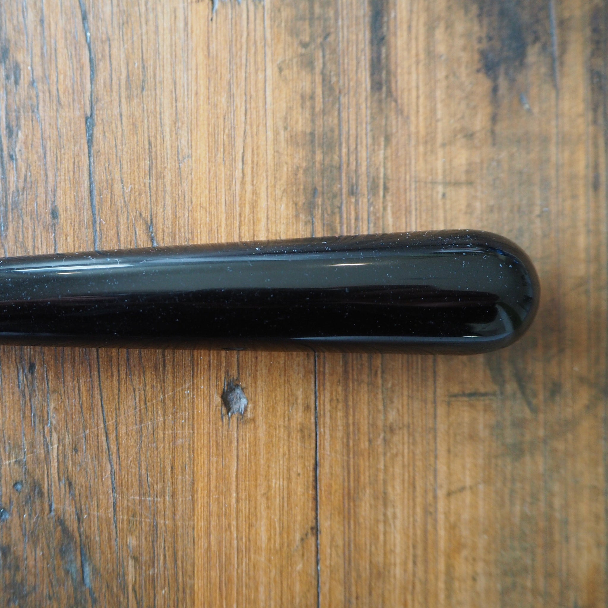 Small black obsidian yoni wand on wooden background